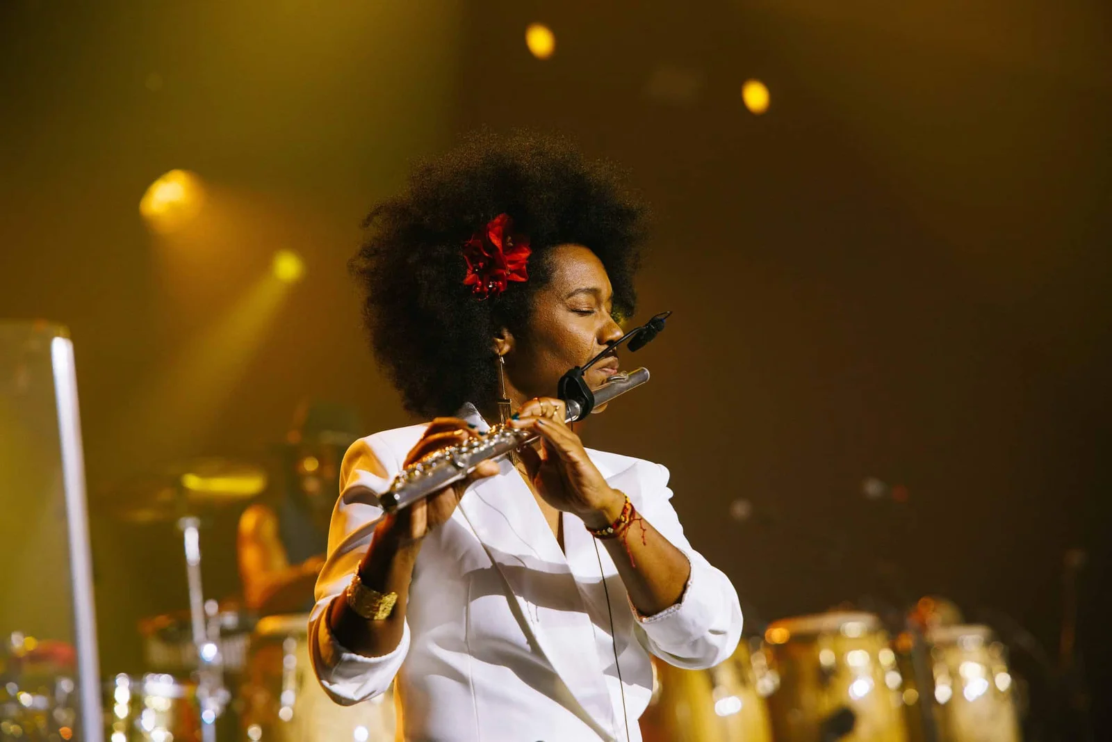 Magela Herrera performing on flute in an intimate golden stage setting